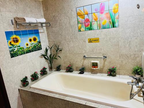 a bath tub in a bathroom with a painting of sunflowers at Max Suites At Barjaya Times Square Kl in Kuala Lumpur
