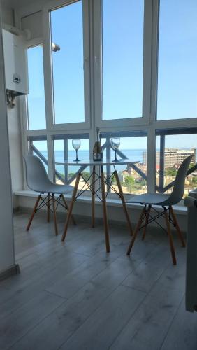 a glass table and two chairs in a room with windows at Квартира з панорамним видом на море in Chornomorsk