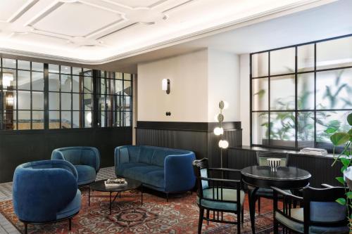 a lobby with blue chairs and tables and windows at Hotel Astoria Vienna, Curio Collection by Hilton in Vienna
