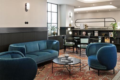 a living room with blue couches and a table at Hotel Astoria Vienna, Curio Collection by Hilton in Vienna