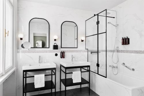 a bathroom with two sinks and a shower at Hotel Astoria Vienna, Curio Collection by Hilton in Vienna