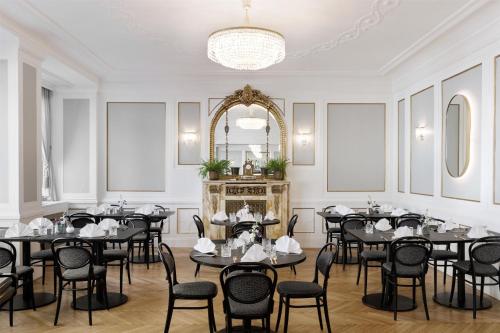 a dining room with tables and chairs and a chandelier at Hotel Astoria Vienna, Curio Collection by Hilton in Vienna