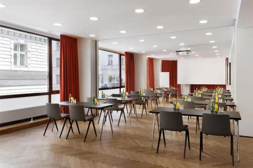 a restaurant with tables and chairs and a large window at Hotel Astoria Vienna, Curio Collection by Hilton in Vienna