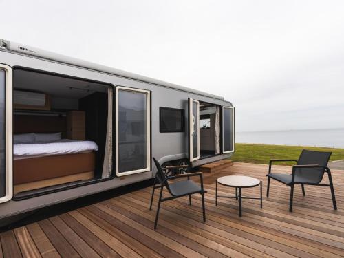 a caravan with chairs and a bed and a table at Aquaignis Awaji Island TRAILER PARK in Awaji