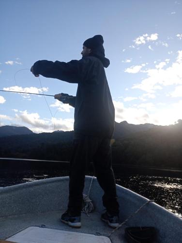 a man standing on the edge of a boat holding a kite at Aromas de Montaña II in Junín de los Andes
