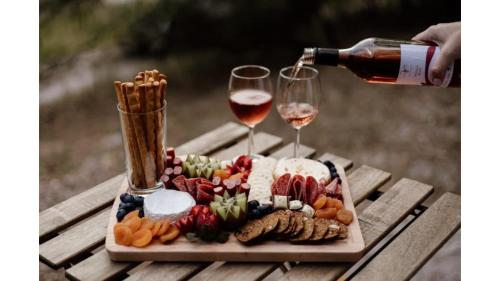 a plate of food and two glasses of wine at Sunset Vine at Wonganella Estate 2 by Tiny Away in Bobs Farm