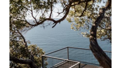 a view of the ocean from behind some trees at Sunset Vine at Wonganella Estate 2 by Tiny Away in Bobs Farm