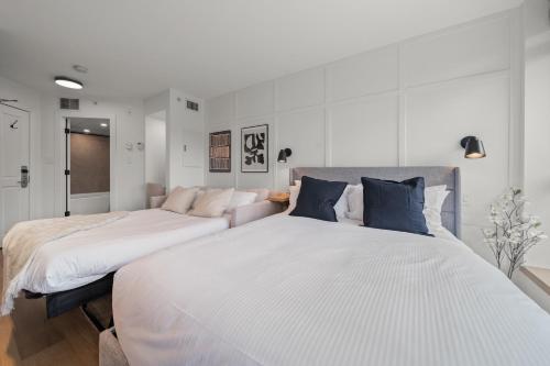 two beds in a bedroom with white walls at The Summit Room Whistler Village in Whistler