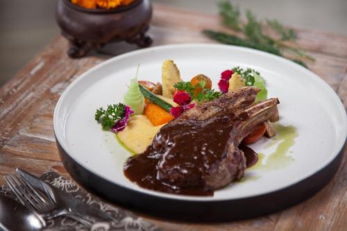 a plate of food with meat and vegetables on a table at thewakanda Resort A Pramana Experience in Ubud