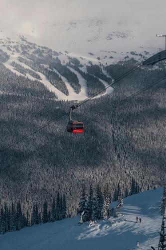 a red ski lift flying over a snow covered mountain at The Summit Room Whistler Village in Whistler