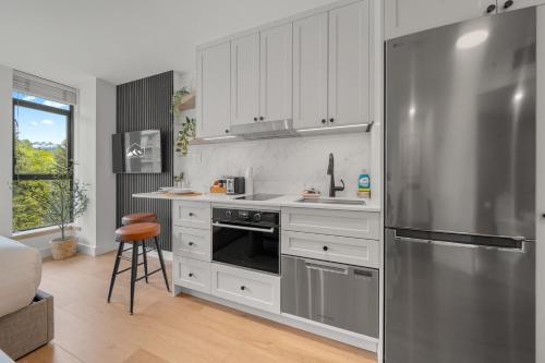 a kitchen with white cabinets and a stainless steel refrigerator at The Summit Room Whistler Village in Whistler