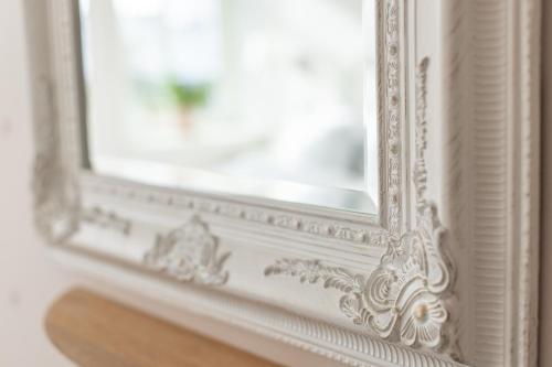 a mirror with a white frame on a wall at Lotshotellet in Käringön