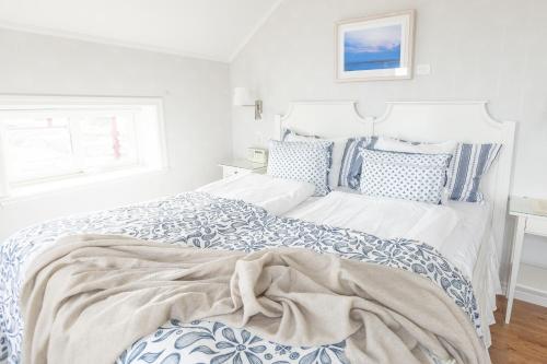 a white bedroom with a bed with blue and white pillows at Lotshotellet in Käringön