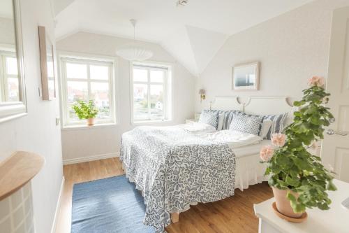 a white bedroom with a bed and a potted plant at Lotshotellet in Käringön