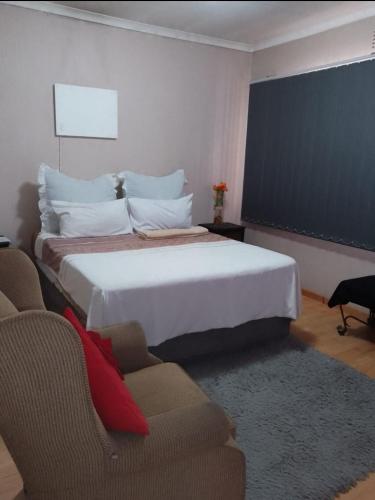 a bedroom with a large white bed and two chairs at Garden View Guesthouse Fleurhof in Johannesburg