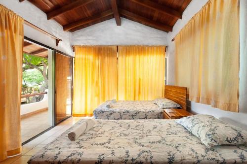 a bedroom with two beds and a window at Casa Majahualt in San Juan del Sur