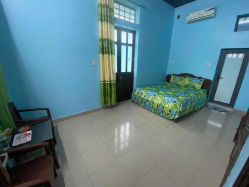 une chambre avec un lit dans une pièce bleue dans l'établissement Minh Anh Homestay Huế, à Ấp Long Hồ Hạ