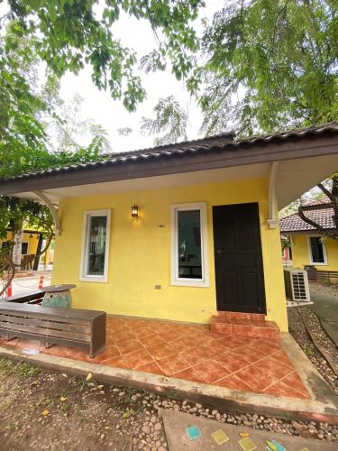 a yellow house with a bench in front of it at Park & Pool Resort in Nong Khai