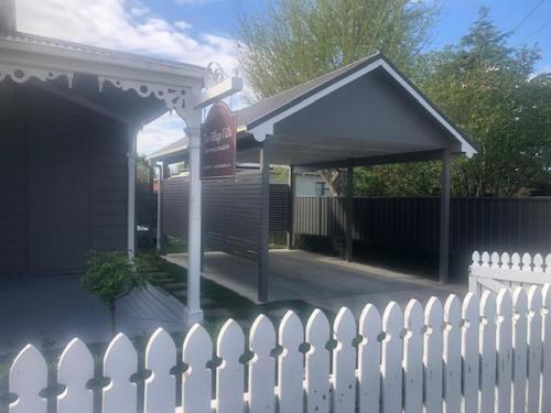 a white fence and a building with a gas station at Luxury Village Villa 200metres from Village in Havelock North