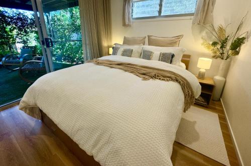 a bedroom with a large white bed with a window at Noosa Bliss - Self Contained, Shared Pool, Tennis, Gym in Noosa Heads