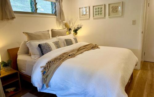 a bedroom with a white bed with pillows and a window at Noosa Bliss - Self Contained, Pool, Tennis, Gym in Noosa Heads