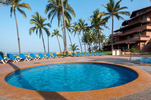 a large swimming pool with chairs and palm trees at Hermoso alojamiento en los Tules, frente al mar en medio de hermosos jardines, es Unico!!! in Puerto Vallarta