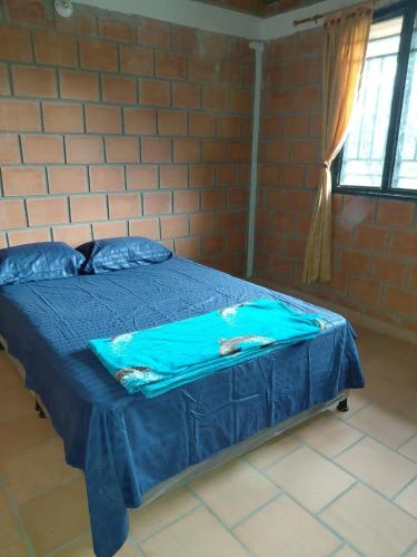 a bedroom with a blue bed in a brick wall at Finca La Macarena in Estación El Salto