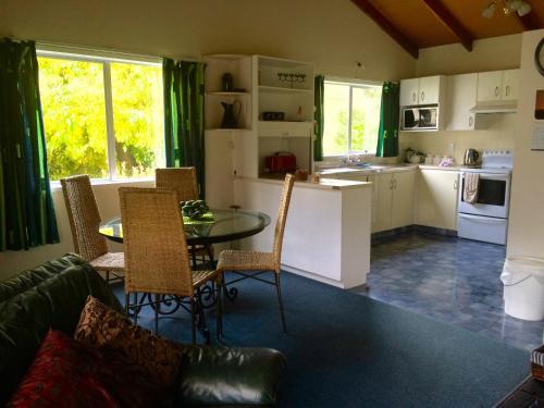 cocina y sala de estar con mesa y sillas en Ohuka Lodge, en Tuai