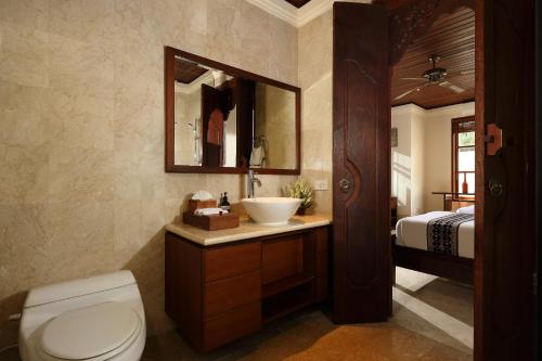 a bathroom with a sink and a toilet and a bed at Jimbaran Beach Villas by Nakula in Jimbaran