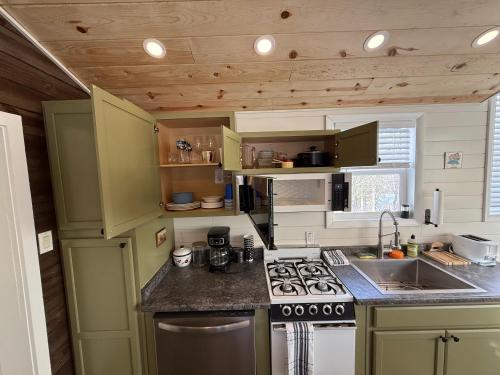 a kitchen with green cabinets and a stove top oven at Tiny Home at Bear Mountain -Only 25 Min from Anchorage, Great Central location-Cute & Comfortable in Anchorage