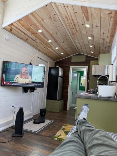 a person laying on a couch in a room with a tv at Tiny Home at Bear Mountain -Only 25 Min from Anchorage, Great Central location-Cute & Comfortable in Anchorage
