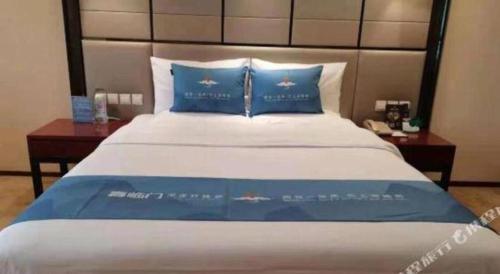 a large bed with blue pillows in a bedroom at Chengdu Antai Century Hotel in Chengdu