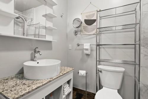 a white bathroom with a sink and a toilet at Chic Mountain View - Pool & HotTub - Fireplace - BBQ! in Canmore