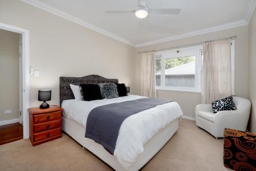 ein Schlafzimmer mit einem Bett und einem Stuhl und einem Fenster in der Unterkunft EAST3 - Coastal Hideaway in Mosman Park