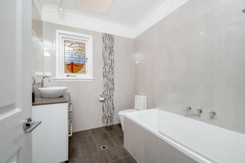 ein weißes Badezimmer mit Badewanne und Waschbecken in der Unterkunft EAST3 - Coastal Hideaway in Mosman Park