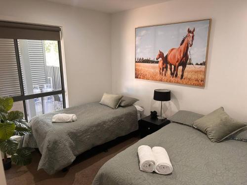 a bedroom with two beds and a painting of two horses at Bundalong Villas in Bundalong
