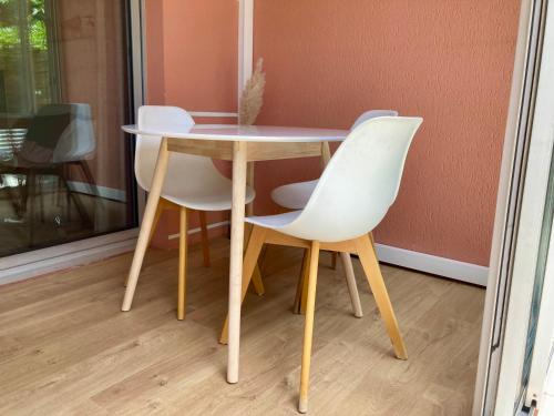 une table et deux chaises blanches assises à côté d'une table dans l'établissement Zen Attitude Apartment, à Cagnes-sur-Mer