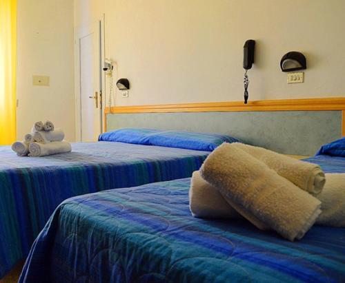 a bedroom with two beds with a teddy bear sitting on top at Hotel Lux in Cesenatico