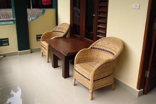 two wicker chairs and a wooden table in a room at Indra Valley Inn Bukit Lawang in Bukit Lawang