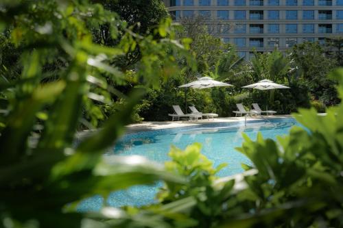 a swimming pool with chairs and umbrellas at Serensia Woods Wellness Resort in Zhuhai