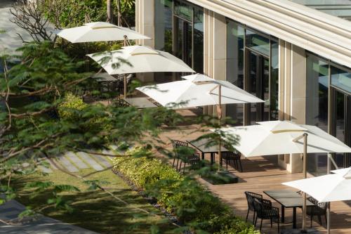 a group of tables with umbrellas in front of a building at Serensia Woods Wellness Resort in Zhuhai