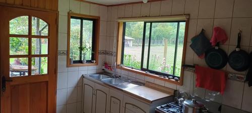 a kitchen with a sink and two windows in it at Casa RamLe in Pucón