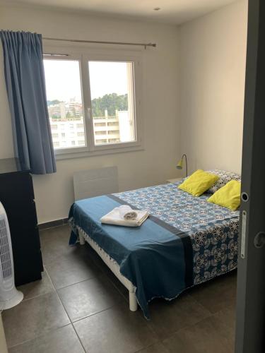 - une chambre avec un lit avec une couette bleue et 2 fenêtres dans l'établissement Quartier BRUNET appartement agréable bien équipé., à Toulon