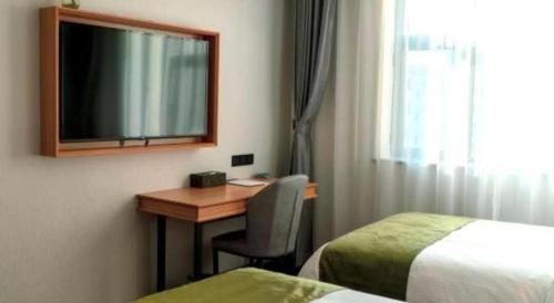a hotel room with a desk with a television and a bed at GreenTree Inn Express Datong High-Speed Railway Station Old City Wall in Datong