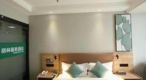 a bedroom with a bed with a phone on it at GreenTree Inn Anqing Yingbin Dong Road High-Speed Railway Station in Anqing