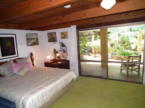 1 dormitorio con 1 cama y puerta corredera de cristal en Shady Grove B&B en Hervey Bay