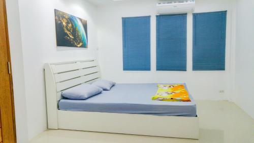 a white bed with blue pillows in a white room at Studio in townhouse with private bath room and kitchenette in Amphoe Phra Khanong