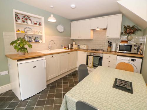 a kitchen with white cabinets and a table in it at Brookside Barn in Bradwell