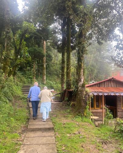 two people walking down a path in the woods at Bloomfield Farmhouse and Eco-Resort in Darjeeling