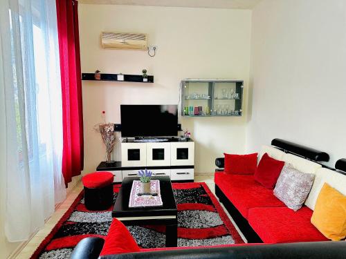 a living room with a red couch and a tv at Domus Komanesse - Guest Houses in Koman